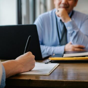 A person seemingly taking notes will having a meeting with a client or colleague